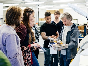 A university professor showing a document to a group of students.