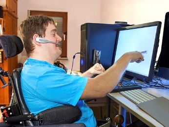 A man in a wheelchair wearing a headset and using a computer. 